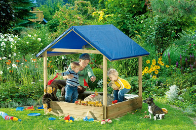 Kinder spielen in einem überdachten Sandkasten in einem Garten